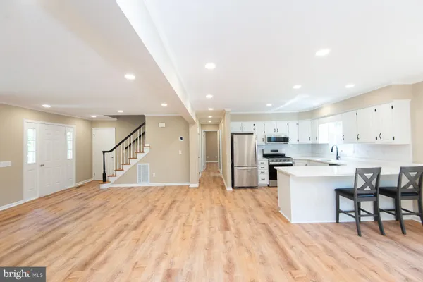 a large white kitchen with lots of counter space a sink stainless steel appliances and cabinets
