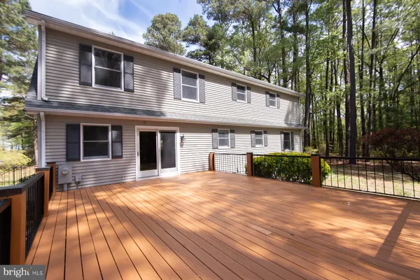 a view of a house with large trees and wooden fence