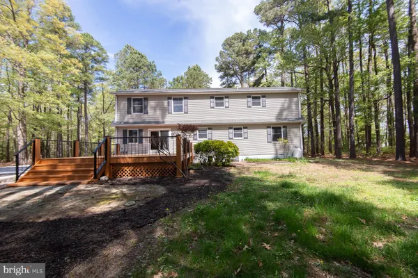 a view of a house with a big yard and large trees