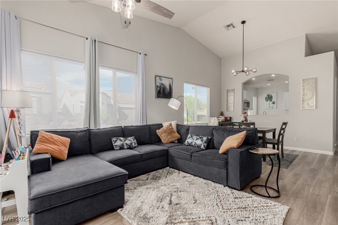 6125 Powdermill Street Las Vegas, NV 89148 - Photo 11 of 33 Living room with light wood-type flooring, arched walkways, a chandelier, a ceiling fan, and high vaulted ceiling