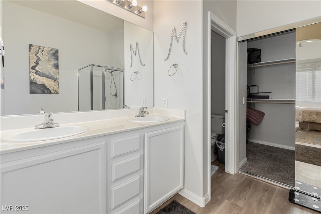 6125 Powdermill Street Las Vegas, NV 89148 - Photo 18 of 33 Full bath with light wood-style floors, double vanity, ensuite bathroom, a stall shower, and a spacious closet