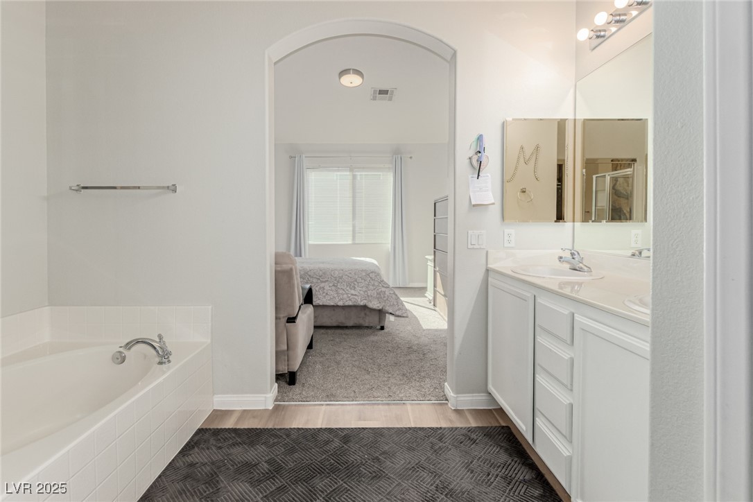 6125 Powdermill Street Las Vegas, NV 89148 - Photo 19 of 33 Bathroom featuring double vanity, ensuite bath, a garden tub, and light wood-style flooring