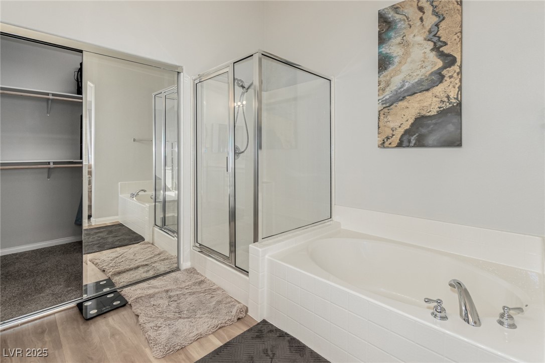 6125 Powdermill Street Las Vegas, NV 89148 - Photo 20 of 33 Bathroom featuring a garden tub, a spacious closet, a shower stall, and wood finished floors