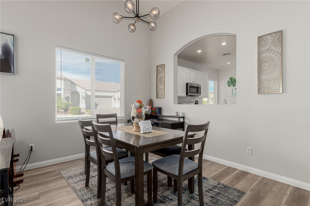 6125 Powdermill Street Las Vegas, NV 89148 - Photo 9 of 33 Dining area with light wood finished floors, a chandelier, arched walkways, and recessed lighting