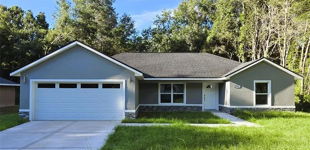 a view of a yard in front of a house with plants and large tree