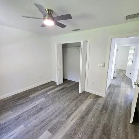 a view of a room with wooden floor and a ceiling fan
