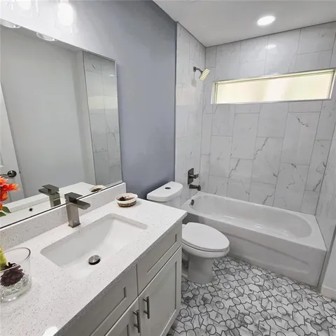 a bathroom with a sink a toilet a mirror and bathtub