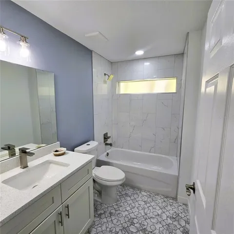a bathroom with a bathtub shower sink vanity mirror and toilet