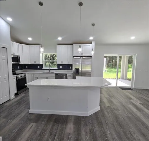 a large kitchen with stainless steel appliances a large counter top a stove and a refrigerator