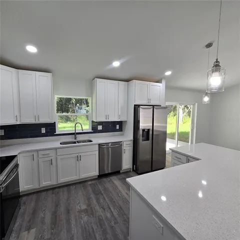 a kitchen with refrigerator a sink and white cabinets