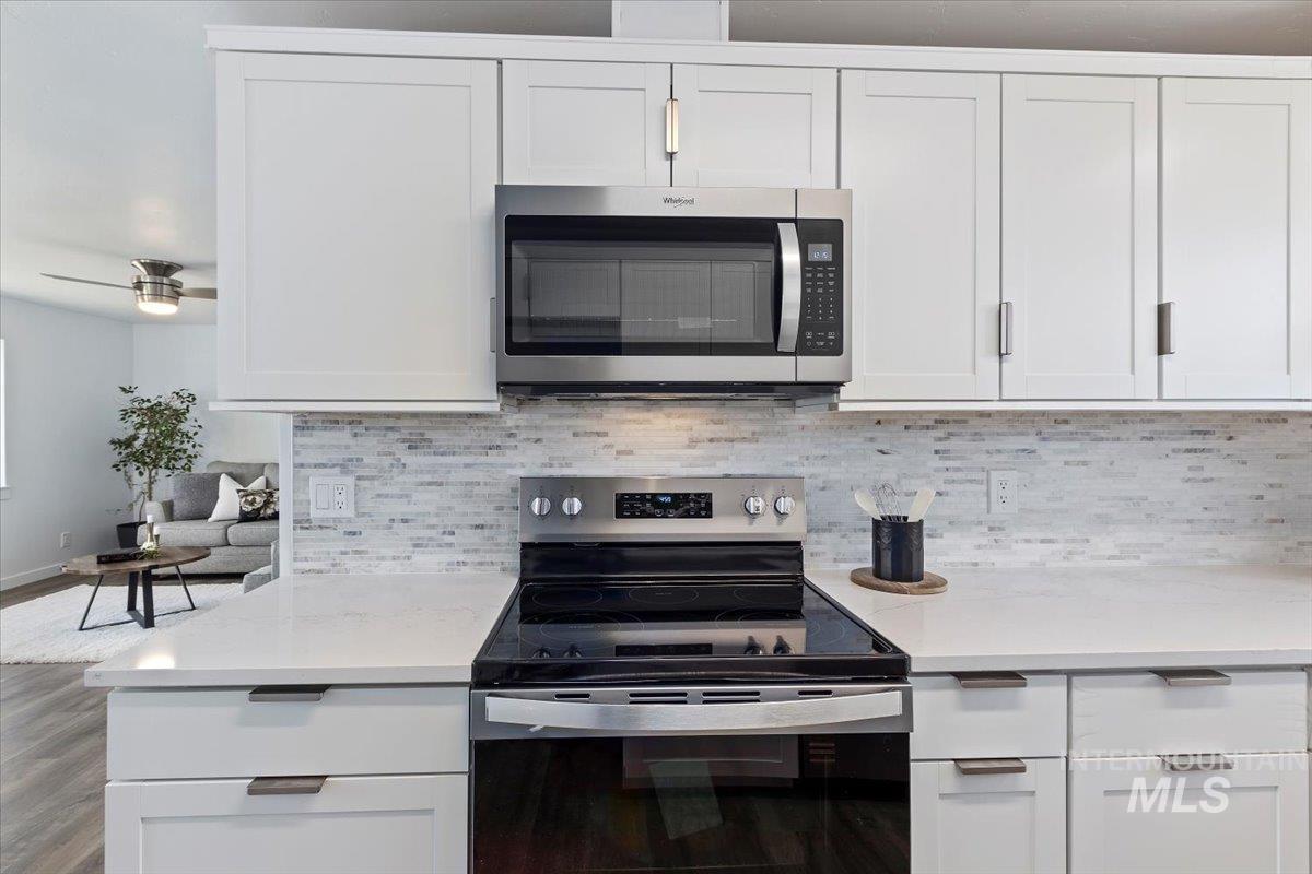 1184 Starfire Street Twin Falls, ID 83301 - Photo 14 of 34 Kitchen featuring stainless steel appliances, white cabinets, decorative backsplash, and light stone counters