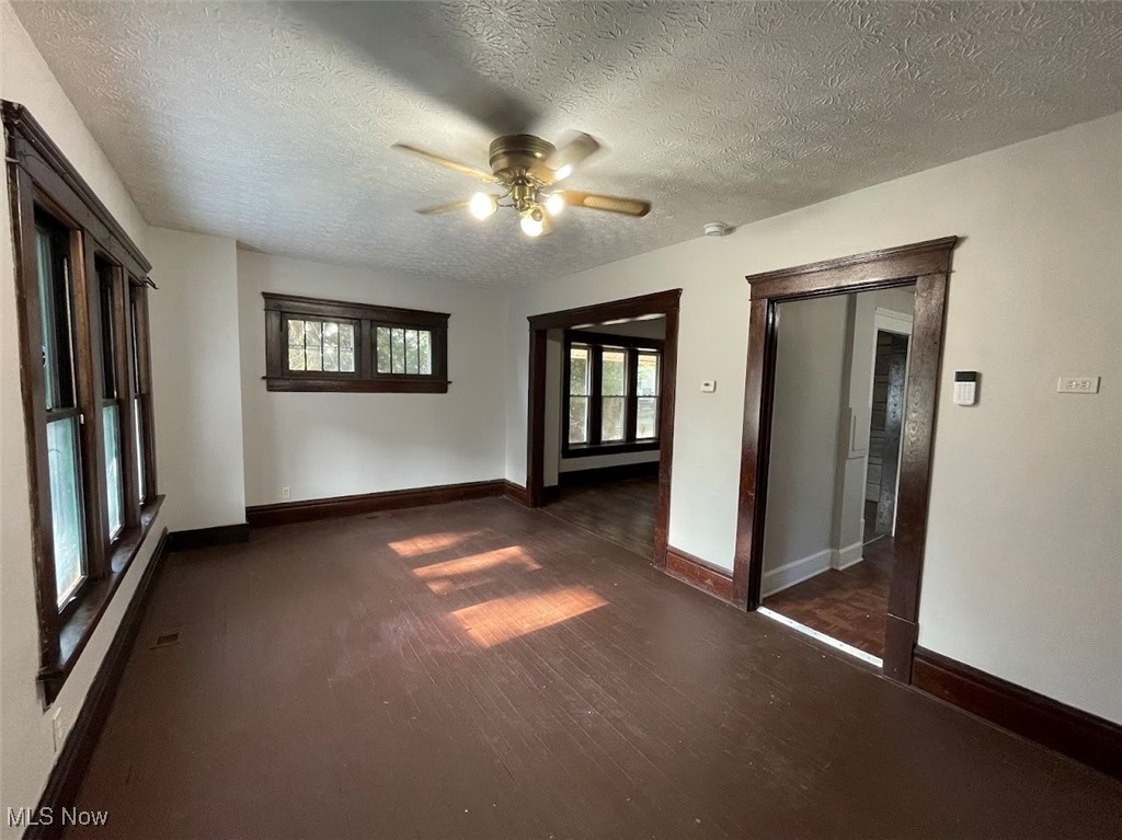 950 Avon Street Akron, OH 44310 - Photo 3 of 15 Unfurnished room with a textured ceiling, dark wood-style flooring, a ceiling fan, and baseboards