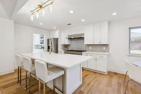 a kitchen with stainless steel appliances granite countertop a sink a stove a refrigerator and island with wooden floor