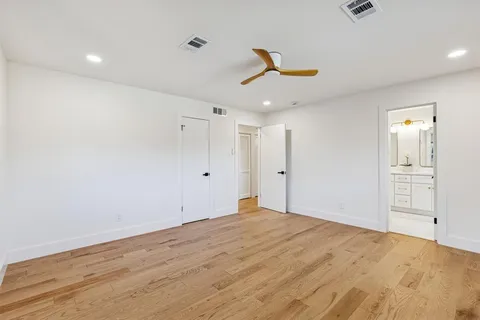 a view of empty room with wooden floor and ceiling fan