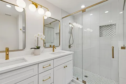 a bathroom with a double vanity sink mirror and shower