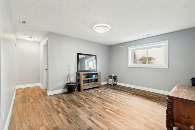 332 East Magellan Lane Elk Ridge, UT 84651 - Photo 15 of 24 Spacious room with wood-finish flooring, light gray wall paint, white baseboards, and a white ceiling