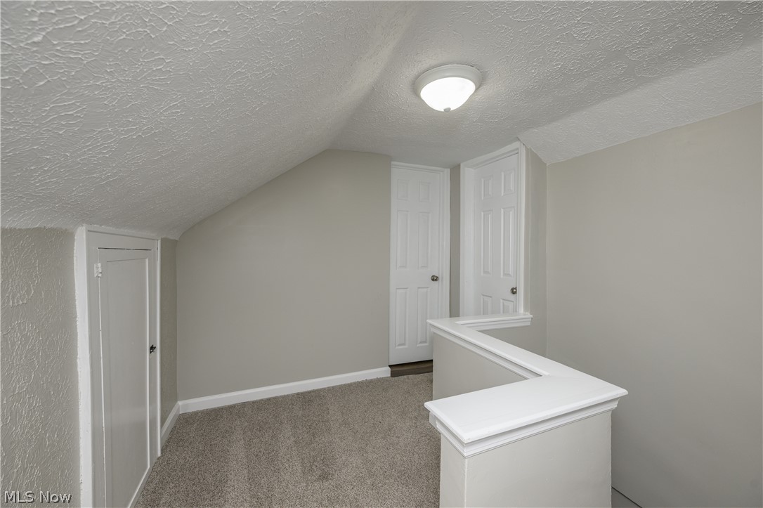6484 Manchester Road Clinton, OH 44216 - Photo 15 of 21 Bonus room featuring a textured ceiling, lofted ceiling, and dark carpet