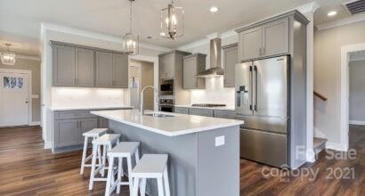3409 Sincerity Road, Unit 15 Monroe, NC 28110 - Photo 6 of 32 a kitchen with stainless steel appliances granite countertop a refrigerator a sink a stove a dining table and chairs with wooden floor