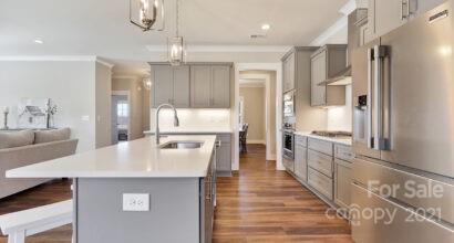3409 Sincerity Road, Unit 15 Monroe, NC 28110 - Photo 7 of 32 a large kitchen with kitchen island a large counter top space a sink stainless steel appliances and cabinets