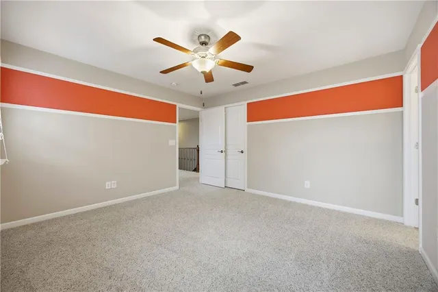 an empty room with closet and a chandelier fan
