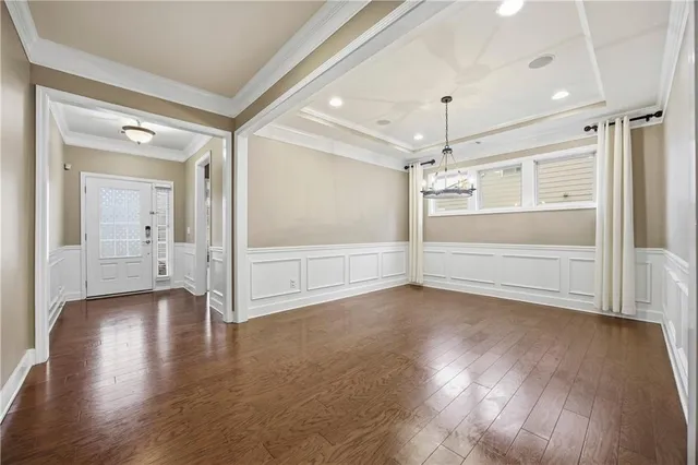 an empty room with wooden floor mirror and windows