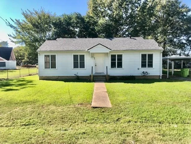 a view of a yard in front of a house with large trees