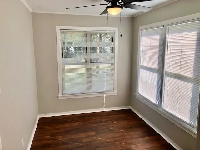 an empty room with wooden floor fan and windows