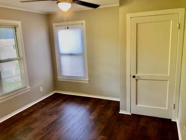 an empty room with wooden floor closet and windows