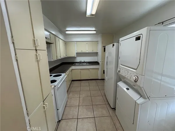 a kitchen with granite countertop a refrigerator a sink and white cabinets