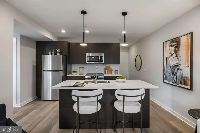 a kitchen with a refrigerator a sink dishwasher a stove and a dining table with wooden floor