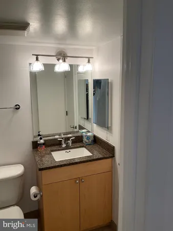 a bathroom with a granite countertop sink a toilet and a mirror
