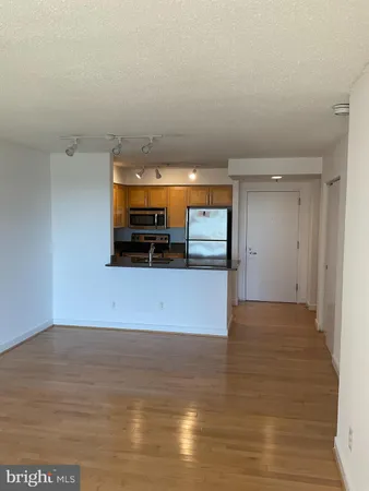 a view of kitchen and empty room with wooden floor