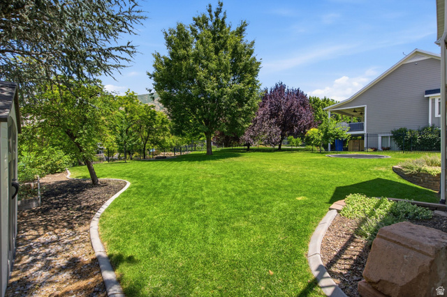 1263 East 1200th South Springville, UT 84663 - Photo 49 of 60 Expansive backyard featuring a manicured lawn, established trees, and defined planting beds with decorative rock
