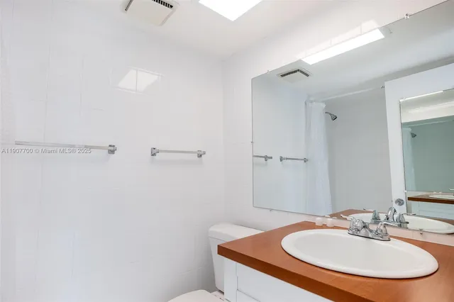 a bathroom with a granite countertop sink mirror vanity and toilet