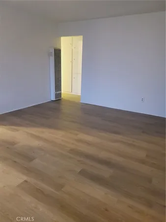 a view of an empty room with wooden floor and a ceiling fan