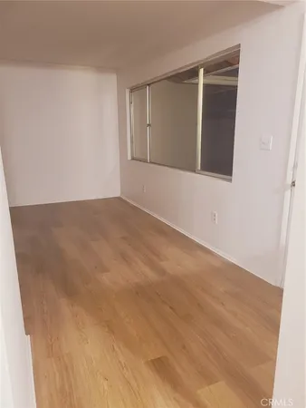 a view of an empty room with wooden floor and fan