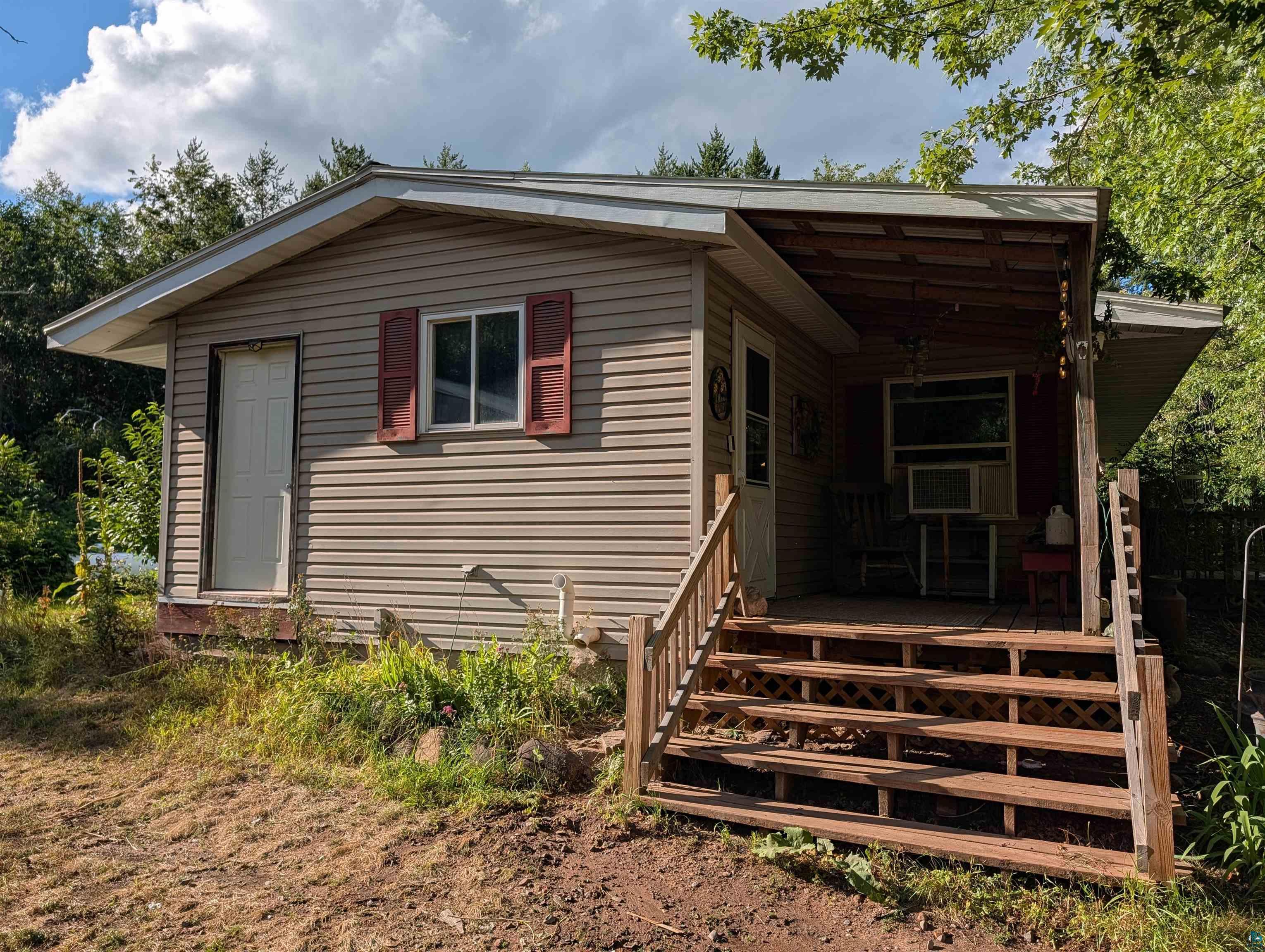 53085 Dupuis Road Sandstone, MN 55072 - Photo 5 of 48 Exterior featuring horizontal siding, red window shutters, and a covered porch with wood steps