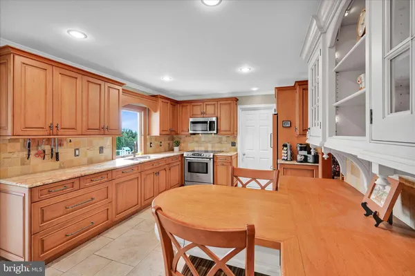 a kitchen with stainless steel appliances granite countertop a refrigerator a sink dishwasher a dining table and chairs with wooden floor