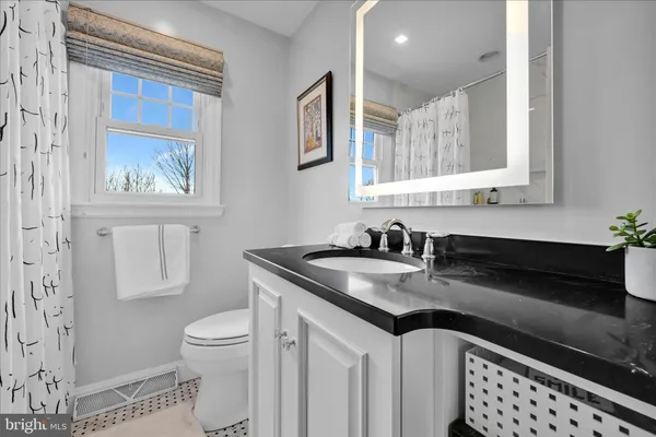 a bathroom with a granite countertop sink mirror vanity and toilet