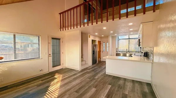 a view of a kitchen with kitchen island granite countertop a large window a sink and a counter top space