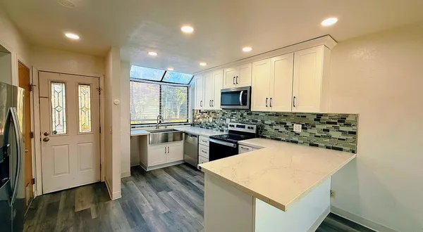 a kitchen with a refrigerator a sink and wooden floor