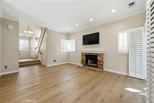 an empty room with windows fireplace and wooden floor