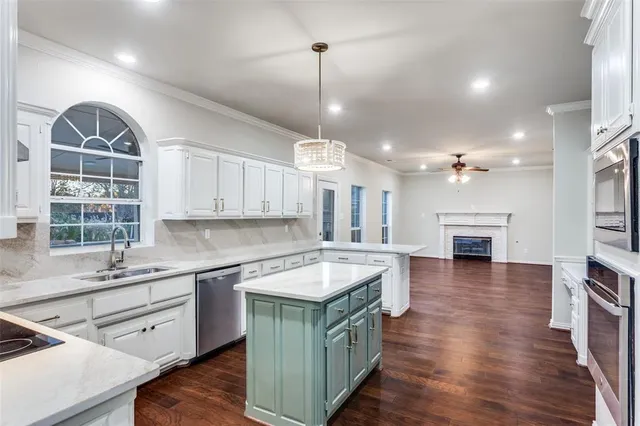 a kitchen with kitchen island granite countertop a sink cabinets and wooden floor