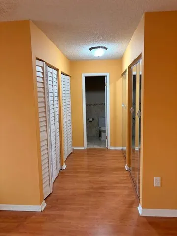 a view of a hallway with wooden floor and closet