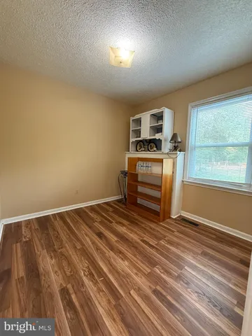 a view of kitchen and empty room with wooden floor