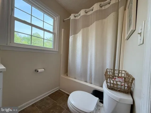 a bathroom with a toilet and a shower curtain