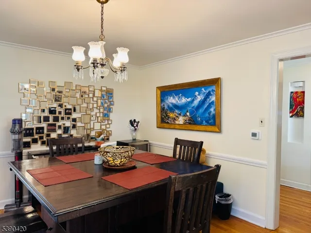 a view of a dining room with furniture a chandelier and wooden floor