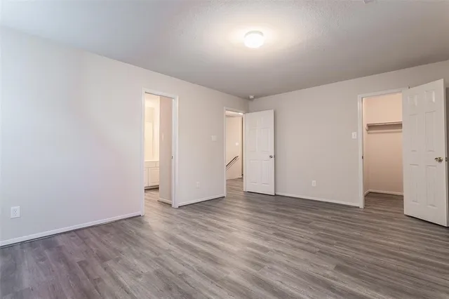 an empty room with wooden floor & windows