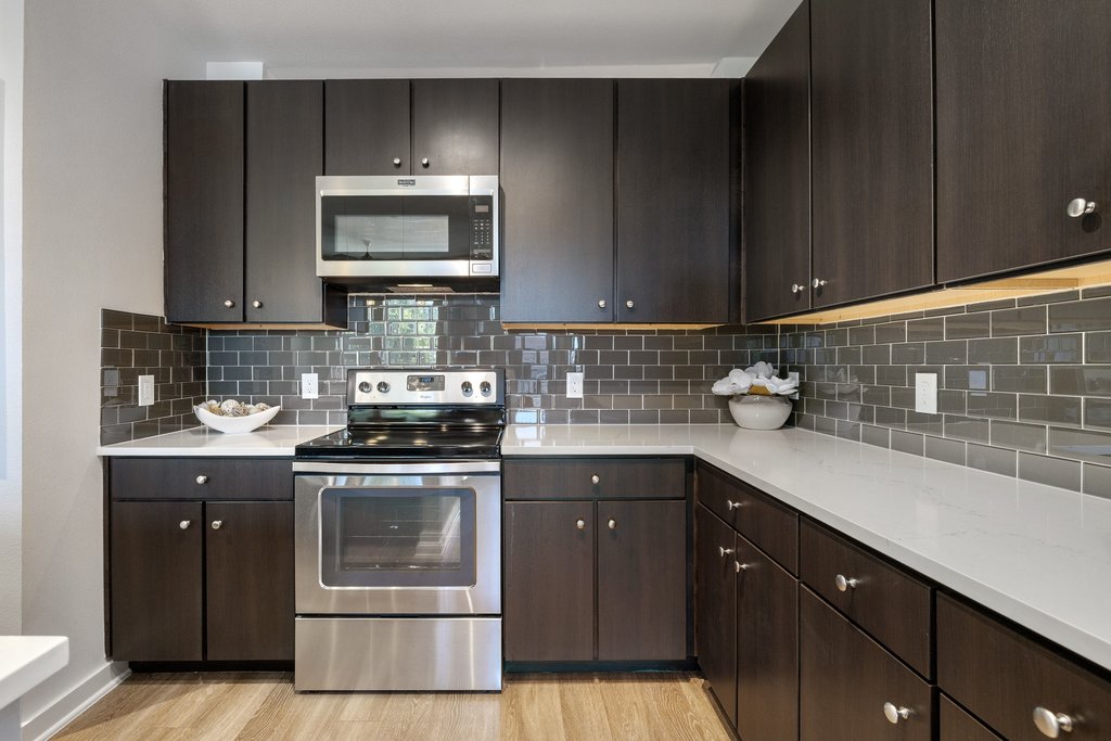 1900 Barton Springs Road, Unit 5009 Austin, TX 78704 - Photo 11 of 35 A well-appointed kitchen features dark cabinetry, white countertops, and stainless steel appliances.