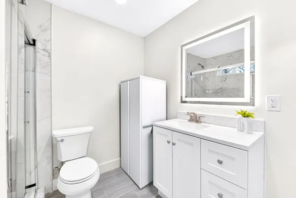 a bathroom with a toilet sink vanity and mirror
